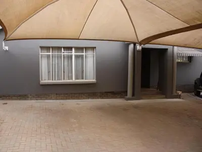 a large umbrella in front of a building with two windows at Blesbok Inn in Polokwane