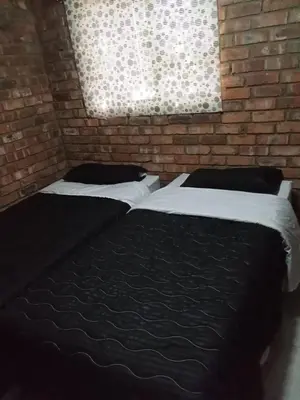 a bedroom with two beds and a brick wall at Secunda BackPackers in Secunda