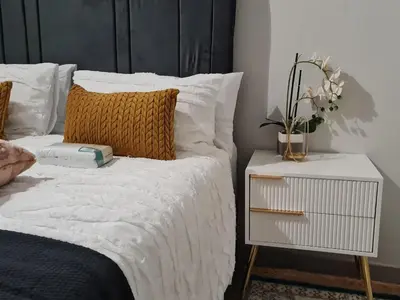 a bedroom with a bed with white sheets and a night stand at Falcon's Nest in Pretoria