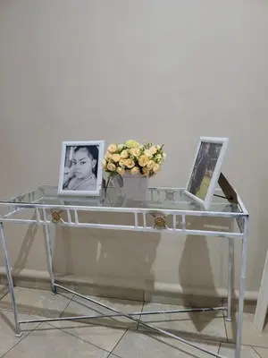 a glass table with two pictures and a vase with flowers at Falcon's Nest in Pretoria