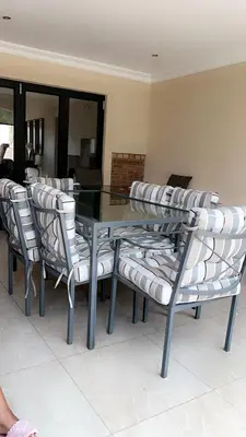 a glass dining room table with chairs and a glass table at Missie Villa 165 on Rooibok Euphoria Golf in Naboomspruit