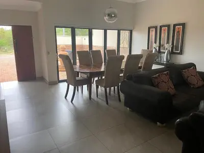 a dining room with a table and chairs and a couch at Missie Villa 165 on Rooibok Euphoria Golf in Naboomspruit