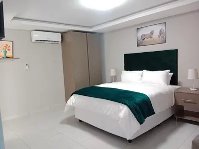 a bedroom with a large bed with a green blanket at CyC Guest Lodge in Giyani