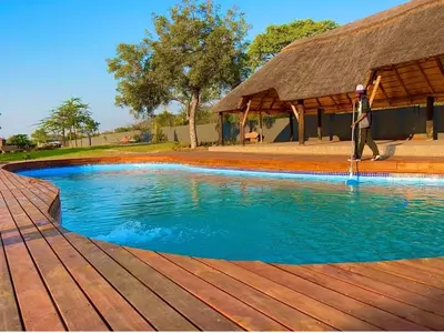 a man walking next to a swimming pool at CyC Guest Lodge in Giyani