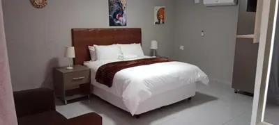 a bedroom with a large white bed with a wooden headboard at CyC Guest Lodge in Giyani