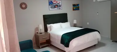a bedroom with a white bed and a chair at CyC Guest Lodge in Giyani