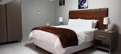 a bedroom with a large bed with a wooden headboard at CyC Guest Lodge in Giyani