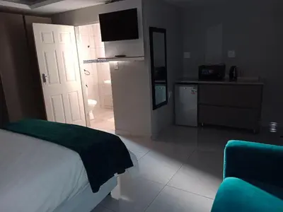a bedroom with a bed and a bathroom with a television at CyC Guest Lodge in Giyani