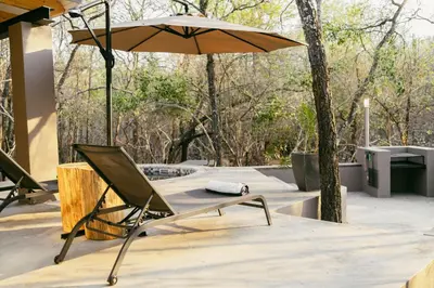 a chair and an umbrella on a patio at Leopard's Khaya, Marloth Park in Marloth Park