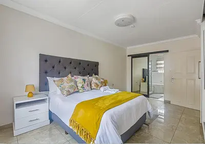 a bedroom with a large bed with a yellow blanket at Signature Lodge in Kempton Park