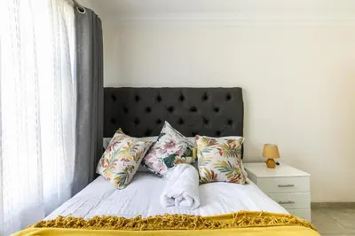 a bedroom with a bed with a black headboard and pillows at Signature Lodge in Kempton Park