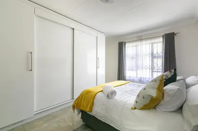a bedroom with a bed with white cabinets and a window at Signature Lodge in Kempton Park