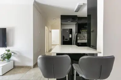 a kitchen with two gray chairs and a white counter at Signature Lodge in Kempton Park
