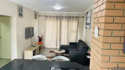 a living room with a couch and a brick wall at Mall Of Africa Spot2 By Damo in Midrand