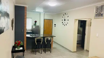 a kitchen with a counter and stools in a room at Mall Of Africa Spot2 By Damo in Midrand