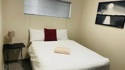 a bedroom with a white bed with a red pillow on it at Mall Of Africa Spot2 By Damo in Midrand