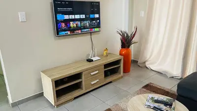 a living room with a flat screen tv on a wall at Mall Of Africa Spot2 By Damo in Midrand