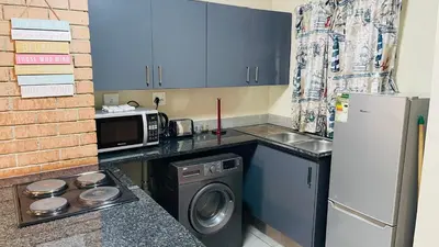 a small kitchen with a refrigerator and a microwave at Mall Of Africa Spot3 By Damo in Midrand