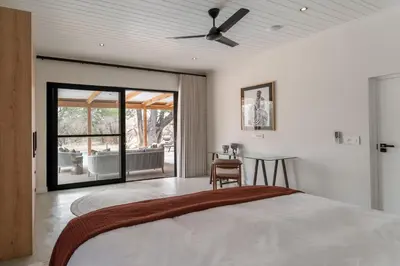 a bedroom with a bed and a ceiling fan at Nomads Den Safari Villas - Heated Pools and Riverbed views in Hoedspruit