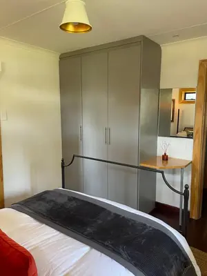 a bedroom with a bed and a desk and cabinets at Idlewood unit 2 in Dullstroom