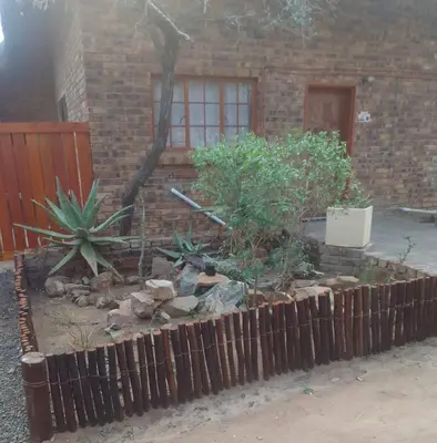 a garden in front of a house with a fence at Bushveld Bliss in Marloth Park