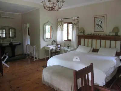 a bedroom with two beds and a table and a desk at Almar View Guest House in Nelspruit