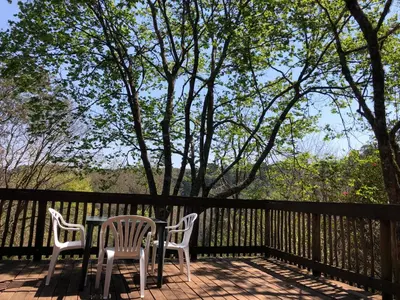 a table and chairs on a deck with a fence at Cheerio Trout Fishing & Holiday Resort in Haenertsburg