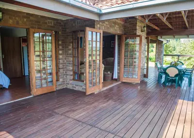 a porch with glass doors and a table and chairs at Cheerio Trout Fishing & Holiday Resort in Haenertsburg