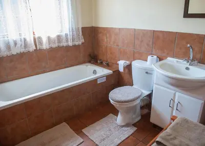 a bathroom with a tub and a toilet and a sink at Cheerio Trout Fishing & Holiday Resort in Haenertsburg