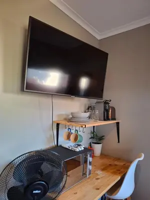 a room with a fan and a television on a wall at Cozy City Studio Escape in Centurion