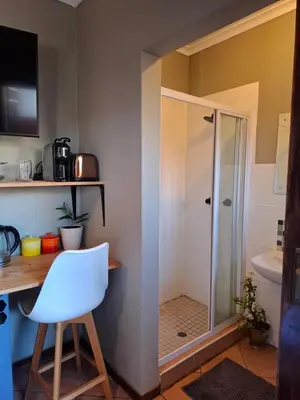 a bathroom with a shower and a desk and a white chair at Cozy City Studio Escape in Centurion
