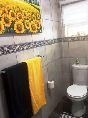 a bathroom with a toilet and a painting of sunflowers at CozyatCaley - Private Apartment in Centurion