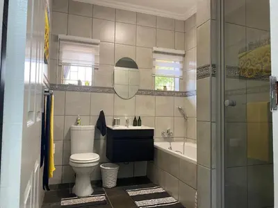 a bathroom with a toilet and a sink and a tub at CozyatCaley - Private Apartment in Centurion