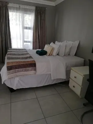 a bedroom with a large white bed with a window at Tenlet guesthouse in Pretoria
