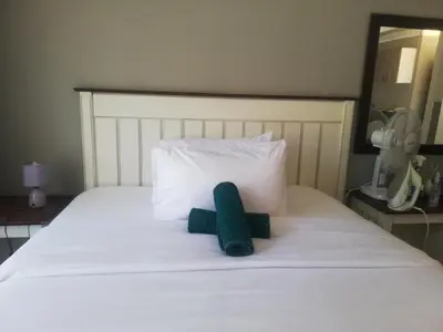 a green stuffed animal sitting on a bed at Tenlet guesthouse in Pretoria