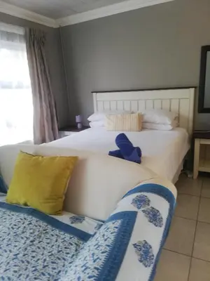 a bedroom with two beds and a couch at Tenlet guesthouse in Pretoria