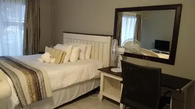 a bedroom with a bed and a desk and a mirror at Tenlet guesthouse in Pretoria