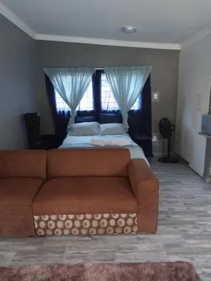 a bedroom with a couch and a bed with curtains at Protea guest house in Pretoria