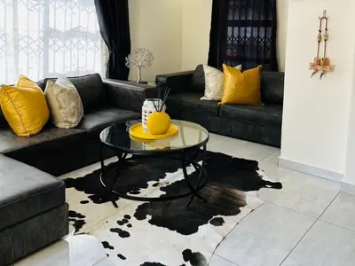a living room with a couch and a table at Khubonye Royal Guesthouse in Randjesfontein