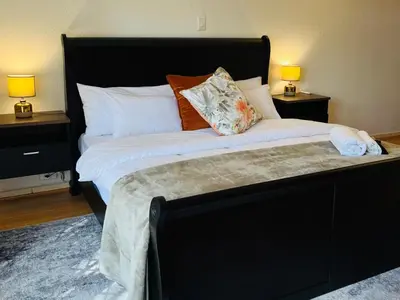 a bedroom with a large black bed with pillows at Khubonye Royal Guesthouse in Randjesfontein