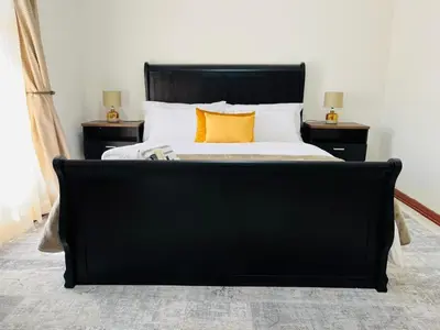 a bedroom with a black bed with two night stands at Khubonye Royal Guesthouse in Randjesfontein