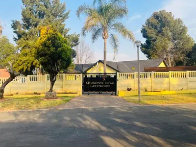 a fence with a sign in front of a house at Khubonye Royal Guesthouse in Randjesfontein