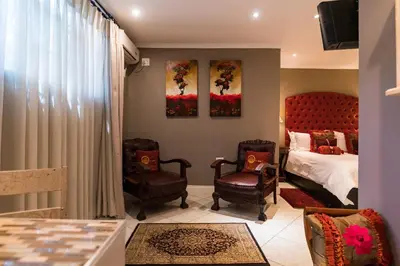 a bedroom with a bed and two chairs at Duke & Duchess Boutique Hotel in Pretoria
