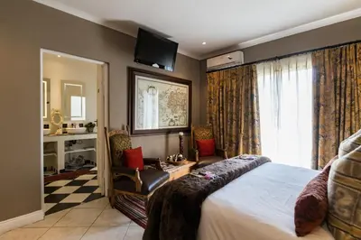 a bedroom with a bed and a tv on the wall at Duke & Duchess Boutique Hotel in Pretoria