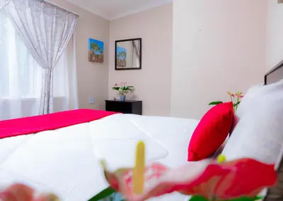 a bedroom with a red and white bed with red pillows at SAR GUESTHOUSE in Benoni