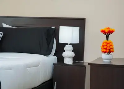 a bedroom with a bed and a lamp and flowers at SAR GUESTHOUSE in Benoni