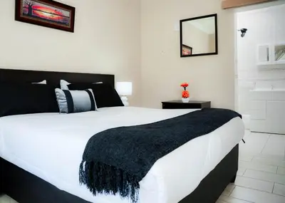 a bedroom with a large white bed with a black blanket at SAR GUESTHOUSE in Benoni