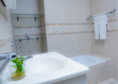 a white bathroom with a sink and a mirror at SAR GUESTHOUSE in Benoni
