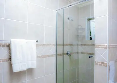 a bathroom with a shower with a glass door at SAR GUESTHOUSE in Benoni