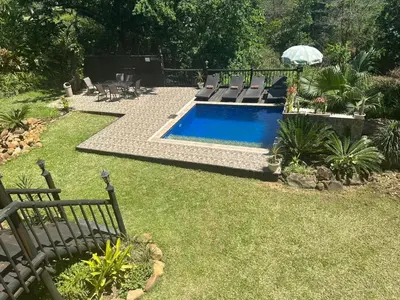 a swimming pool in a yard with chairs and an umbrella at Safari Bed & Breakfast in Hazyview